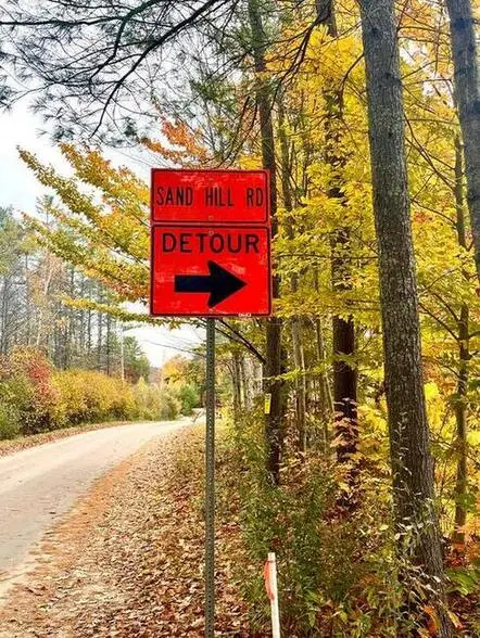 Photo of an orange detour sign on the side of a road.